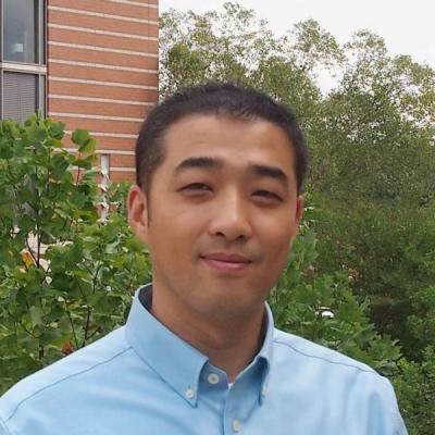 Dr. Kyu Lee standing outside of building with plants behind